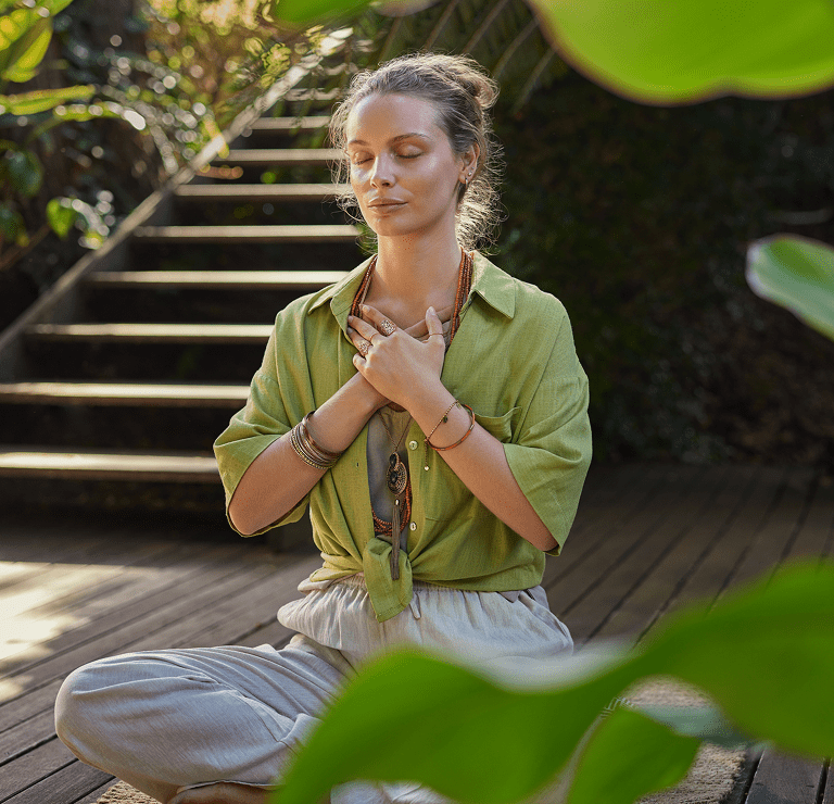Woman meditating outdoors with closed eyes.