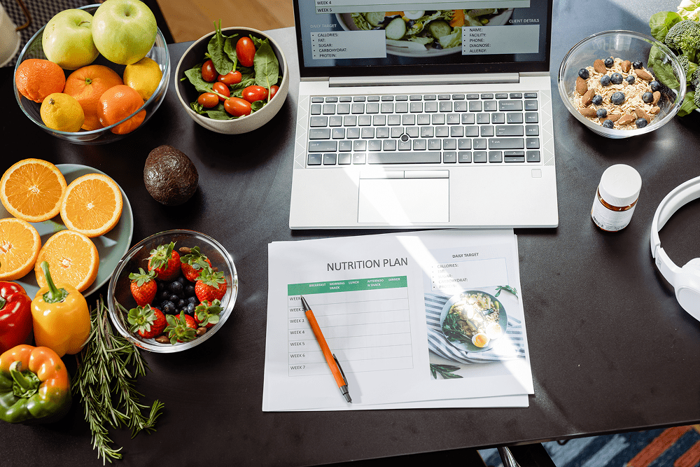 Healthy meal planning with laptop and fruits.